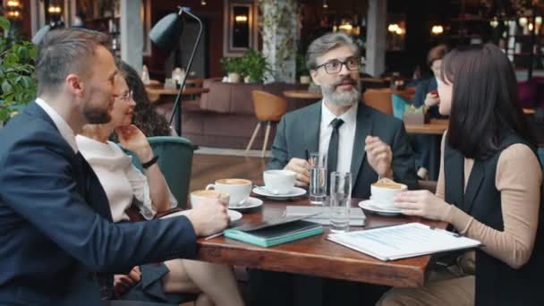 Los empresarios alegres mujeres y hombres hablando y riendo en la mesa en la cafetería — Vídeo de stock