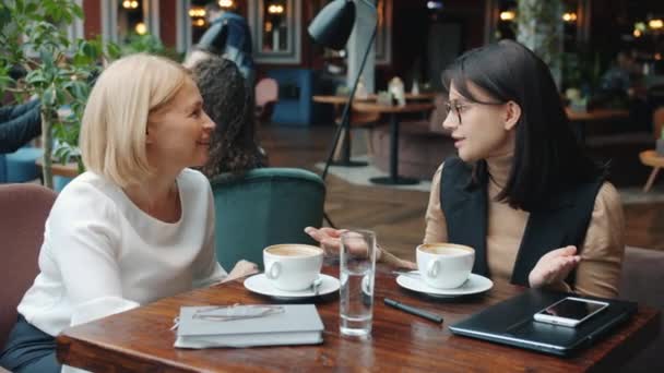 Веселі ділові жінки розмовляють в кафе, а потім роблять п'ять, насолоджуючись успішним партнерством — стокове відео