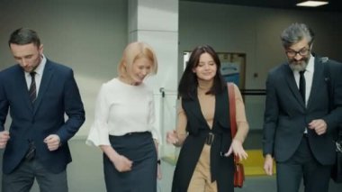 Bir grup iş adamı ve kadın lobide dans ediyor ve birlikte eğleniyorlar.