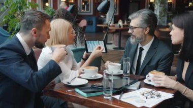 Restorandaki iş ortaklarıyla görüşmeler sırasında tablet kullanan olgun iş kadını.