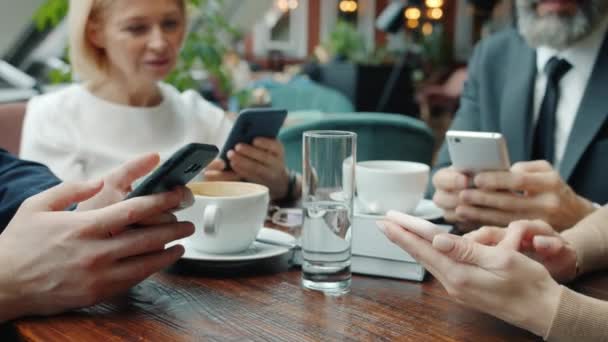 Close-up of hands using smart phones in restaurant, businesspeople enjoying social media during lunch break — Stock Video