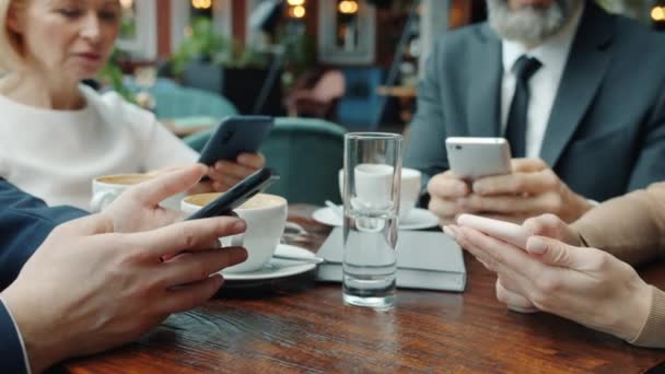 Affärsmän som använder smartphones koncentrerade på enheter i restaurang — Stockvideo