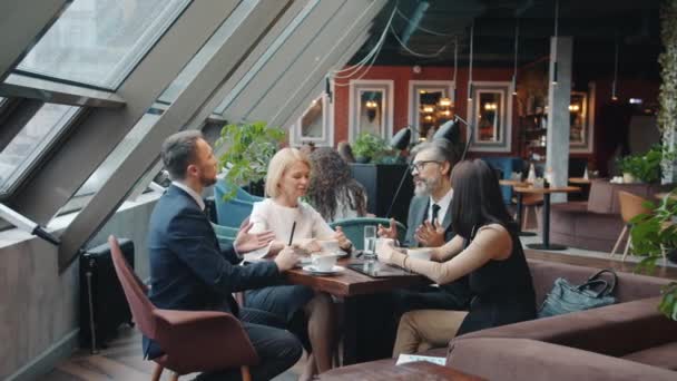 Parceiros de compras homens e mulheres discutem acordo em restaurante conversando e gesticulando — Vídeo de Stock