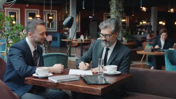 Empresarios en ropa formal usando teléfonos inteligentes tocando la pantalla en la mesa en la cafetería — Vídeos de Stock