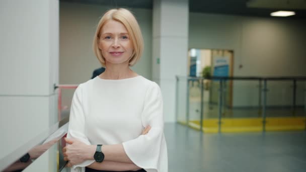 Portret van een vrolijke, volwassen vrouw die glimlachend op kantoor staat en naar de camera kijkt — Stockvideo