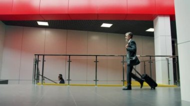 İş merkezinde valiziyle havaalanına giden bir ofis çalışanının ağır çekimde yürümesi.