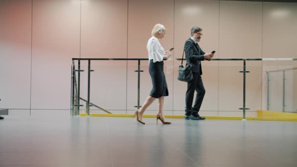 Les hommes d'affaires en coffrage se déplaçant dans le hall de l'immeuble de bureaux à l'aide de gadgets roulants valise — Video