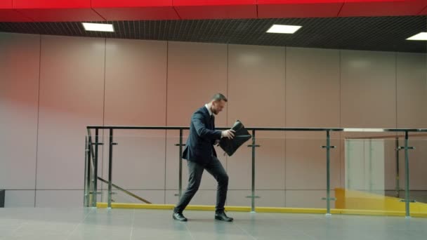 Mouvement lent de joyeux homme d'affaires dansant dans le hall du bureau pendant que les gens se promènent — Video