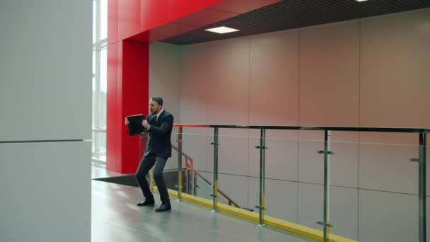 Emocionado joven en traje bailando en el lobby del centro de negocios divirtiéndose disfrutando del éxito — Vídeo de stock