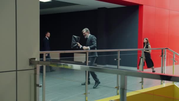 Langzame beweging van grijs-harige zakenman dansen in kantoor foyer blij met succes — Stockvideo