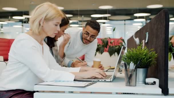 Cámara lenta de colegas que usan computadoras portátiles y hablan en la oficina de espacio de trabajo compartido — Vídeos de Stock