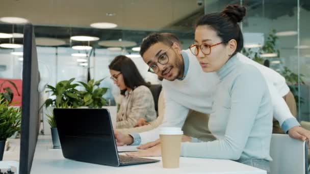 Kolegové mluví při pohledu na obrazovku notebooku pracující s počítačem ve sdílené kanceláři — Stock video