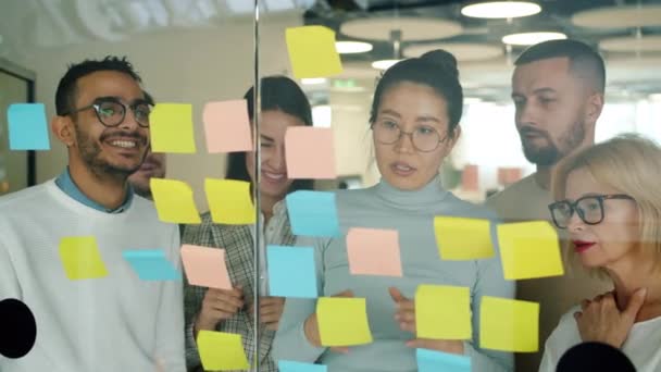 Pessoas alegres colegas trabalhando no escritório com notas pegajosas falando rindo — Vídeo de Stock