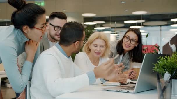 Grupo multirracial de personas hablando sobre el trabajo mirando a la pantalla del ordenador portátil en la oficina compartida — Vídeo de stock