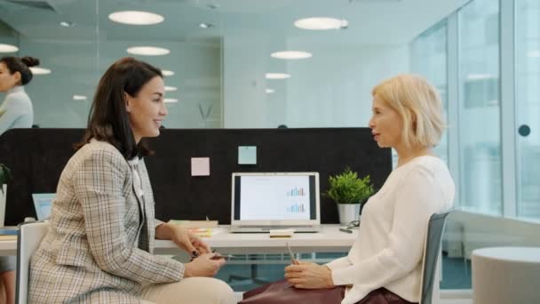 Zeitlupe von Geschäftsfrauen, die jung und reif am Schreibtisch im Büro reden — Stockvideo