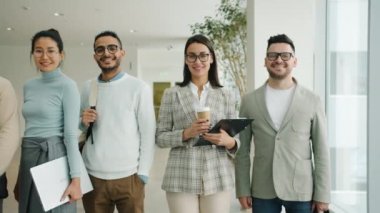 Lobide kameraya bakıp gülümseyen çok ırklı profesyonellerin portresi.