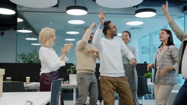Happy Arab man dancing with multi-ethnic froup of colleagues in shared office — Stock Video