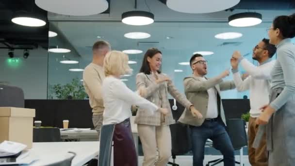 Ortak ofiste dans eden neşeli iş arkadaşlarının ağır çekimde birlikte eğlenmesi. — Stok video