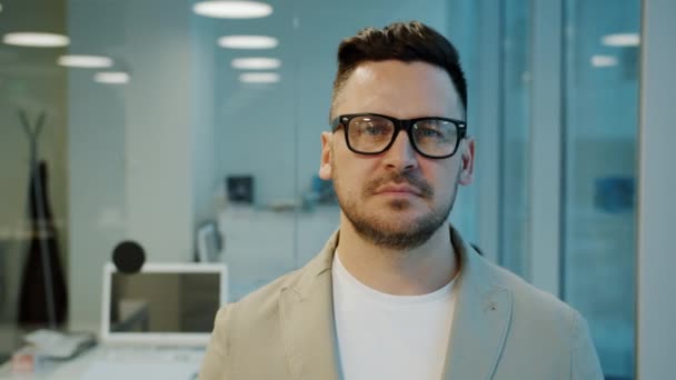 Mouvement lent de l'homme sérieux d'âge moyen dans des lunettes debout dans le bureau le soir — Video