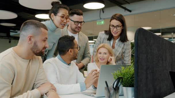 Kreativ-Team diskutiert Projekt mit Blick auf Laptop-Bildschirm und klatscht dann in die Hände — Stockvideo