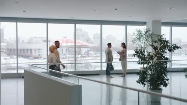 Zoom-in de homem e mulher conversando no lobby enquanto colegas andando por aí — Vídeo de Stock