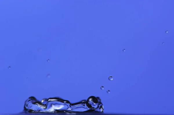 Wasserspritzer auf blauem Hintergrund mit Kopierraum — Stockfoto
