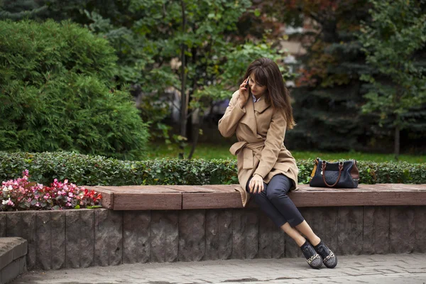 Jovem bela mulher sentada em um banco no parque de outono — Fotografia de Stock