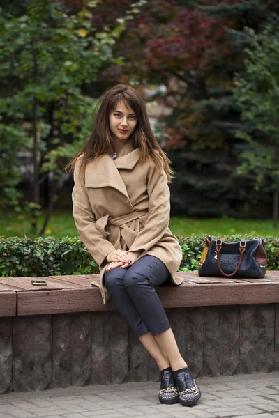Молода красива жінка сидить на лавці в осінньому парку — стокове фото