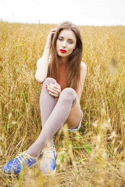Ung vacker kvinna som sitter i ett fält — Stockfoto