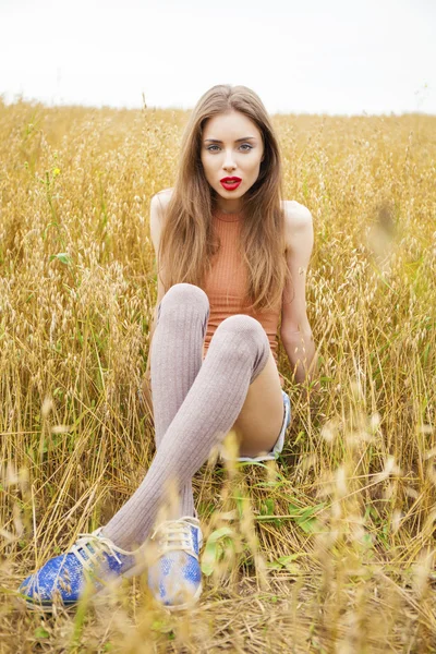 Jovem bela mulher sentada em um campo — Fotografia de Stock