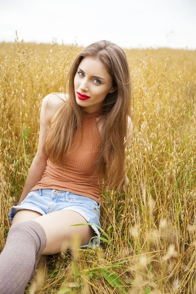 Joven hermosa mujer sentada en un campo — Foto de Stock