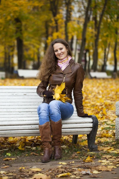 Νεαρή γυναίκα που κάθεται στον πάγκο στο πάρκο φθινόπωρο — Φωτογραφία Αρχείου