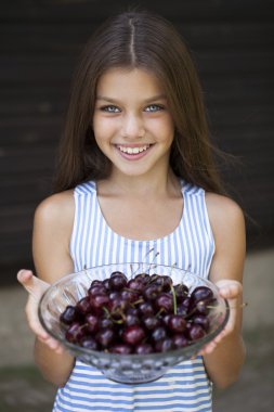 Güzel kız bahçede bir kase kiraz tutuyor.