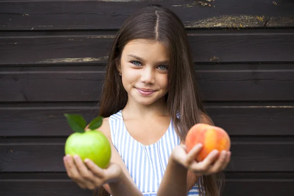 Little girl holding a green apple and a peach — Stock Photo, Image