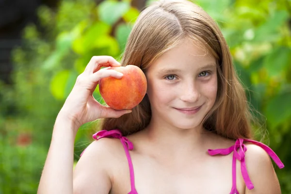 Portrait of a young blonde little girl with peach — Stock Photo, Image