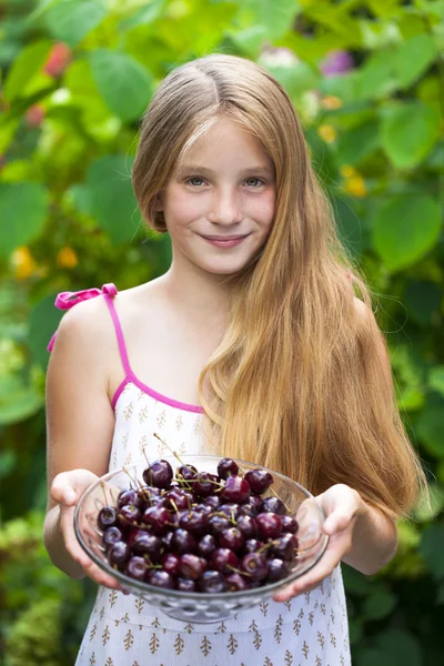 Krásná dívka drží misku třešní v zahradě — Stock fotografie