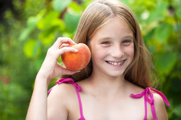 Portrait of a young blonde little girl with peach — Stock Photo, Image