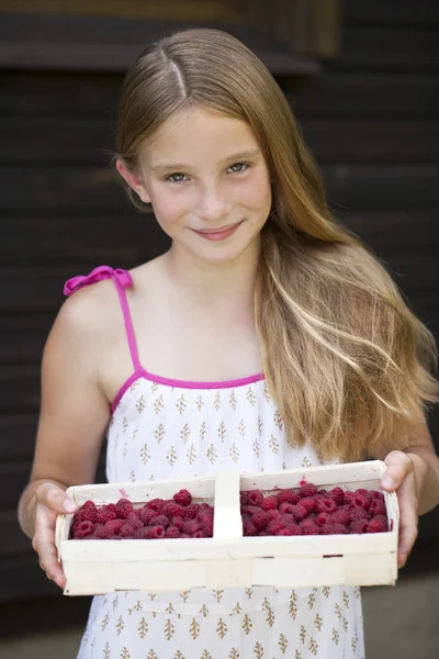 Beautiful girl holding a box with a raspberry — Stock Photo, Image