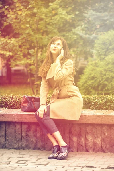 Młoda piękna kobieta siedzi na ławce w parku jesień — Zdjęcie stockowe