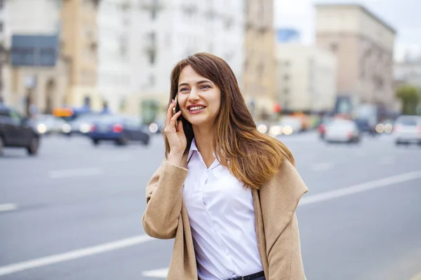 Retrato de jovem morena feliz no casaco bege falando sobre — Fotografia de Stock