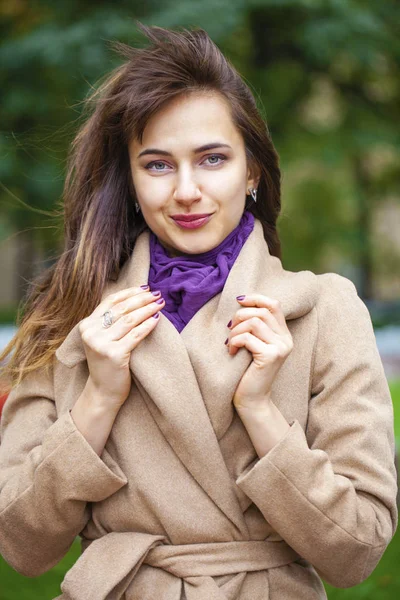 Portræt af en ung smuk kvinde i beige frakke - Stock-foto