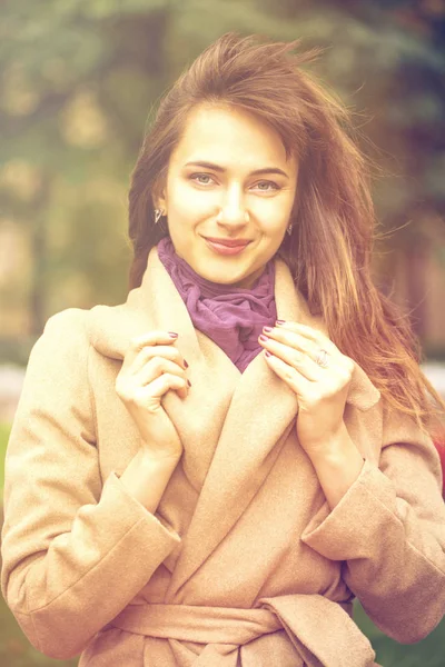 Portræt af en ung smuk kvinde i beige frakke - Stock-foto