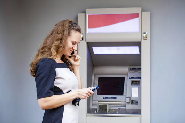 Mujer joven insertando una tarjeta de crédito en el cajero automático —  Fotos de Stock