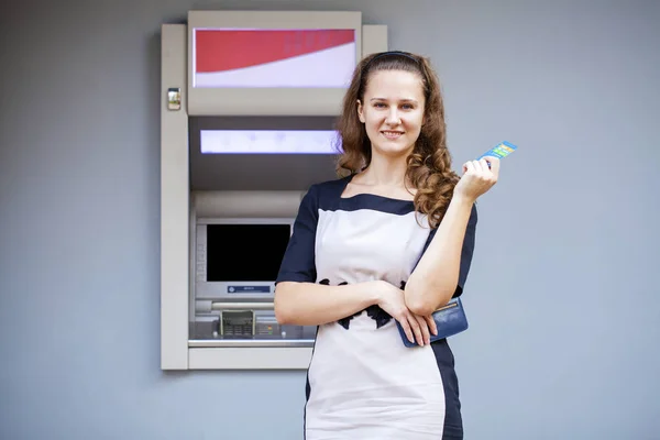 Mujer joven insertando una tarjeta de crédito en el cajero automático —  Fotos de Stock