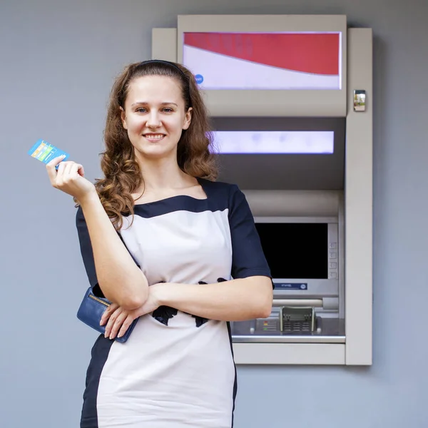 Mujer joven insertando una tarjeta de crédito en el cajero automático — Foto de Stock