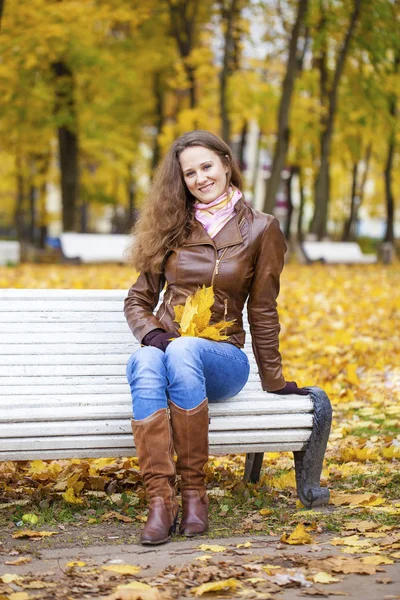 Jeune femme assise sur un banc dans le parc d'automne — Photo