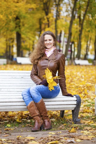 Jeune femme assise sur un banc dans le parc d'automne — Photo