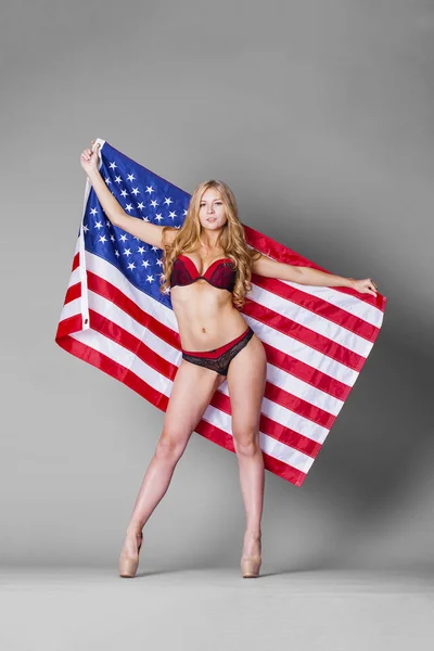 アメリカの国旗を保持している赤いランジェリーの若くてきれいな女性 — ストック写真