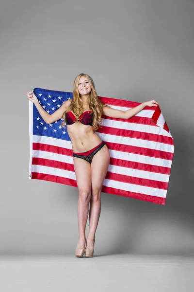 Young beautiful woman in red lingerie holding American flag — Stock Photo, Image