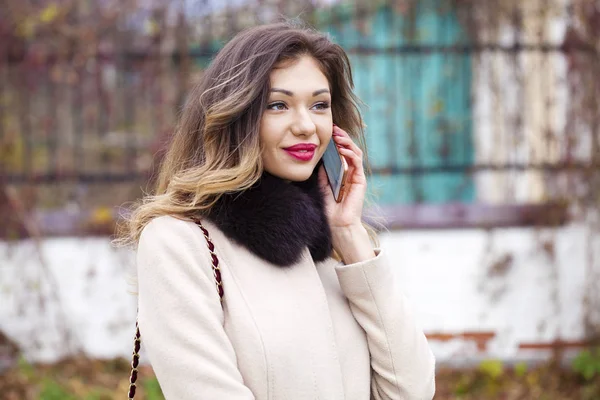 Bej sonbahar montlu genç güzel kadın üzerinde iletiyi okur 